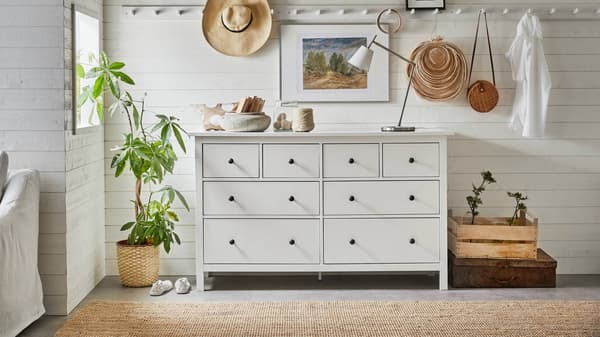 Cómoda HEMNES blanca de 8 cajones, con una lámpara, velas y artículos decorativos en su superficie.