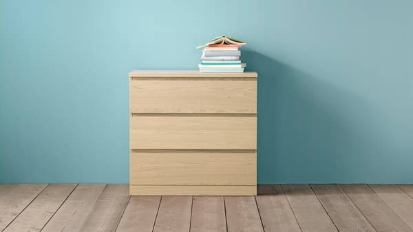 Cómoda MALM de 3 cajones con libros en su superficie.