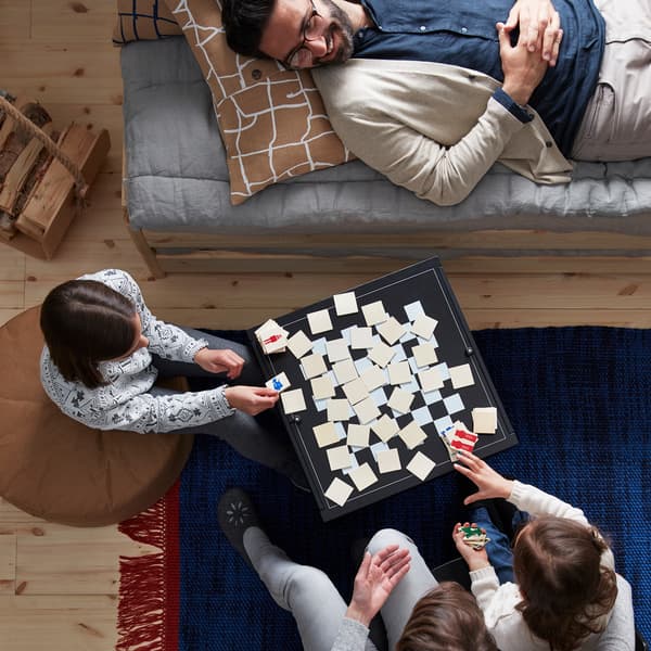Componenti di una famiglia seduti e sdraiati mentre giocano a carte su un tavolino.