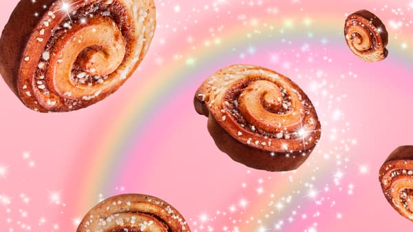 Composición de rollos de canela IKEA con glaseado flotando en un fondo rosado con un arcoiris con brillo en el fondo.