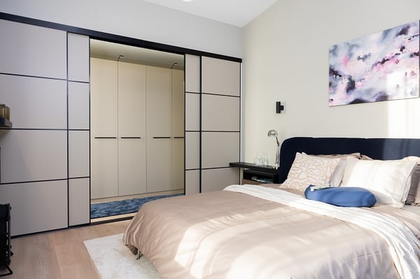 Contemporary bedroom with sliding wardrobe doors, neutral colors, and soft lighting