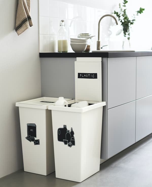 Contenedores de reciclaje FILUR blancos con logos negros. Están apoyados en un mueble gris de cocina.