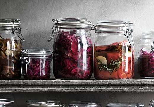 Contenitori in vetro trasparente con cavolo rosso sottaceto e peperoni.