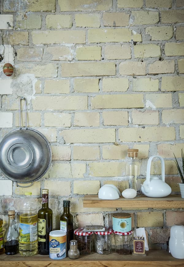 Cooking ingredients on open shelving against a brick wall.