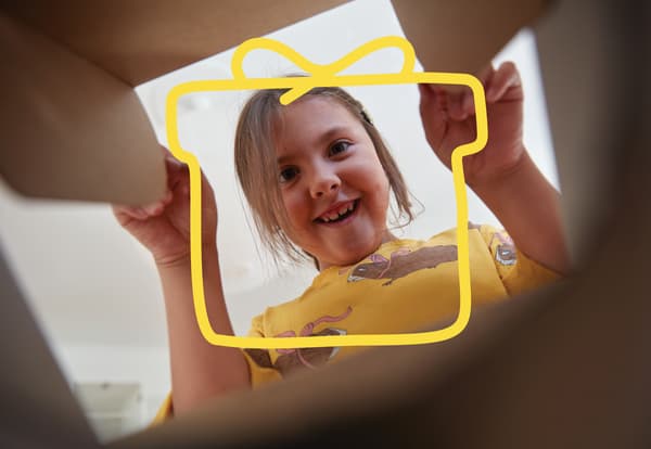 Copil privit de jos în sus, ca din interiorul unei cutii, purtând tricou galben cu desene. 