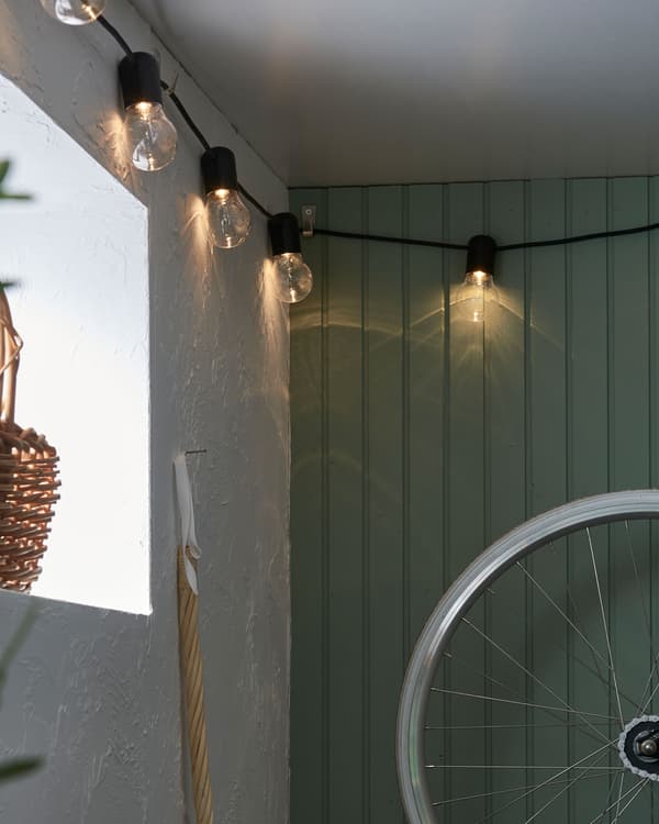 Corner of a basement or garage decorated with a lit lighting chain hung along the wall near the ceiling.