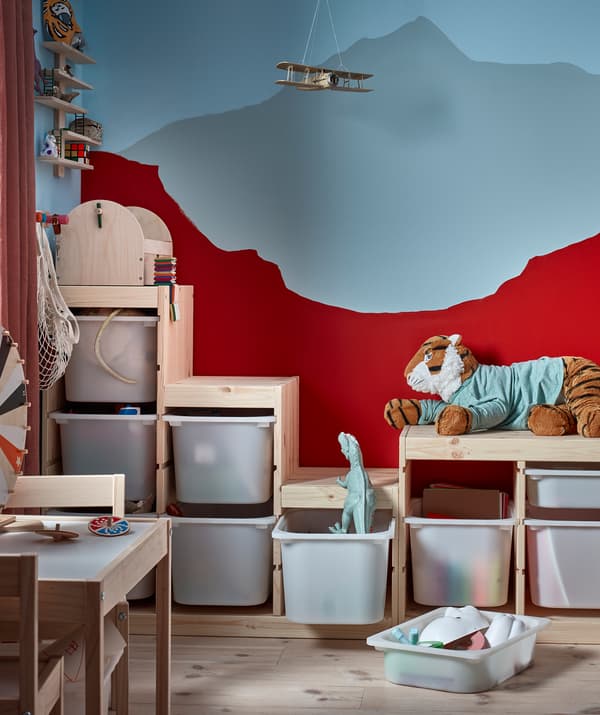 Corner of a kid's room where the uneven outline of a toy-filled shelving unit matches the colouring of the back wall.