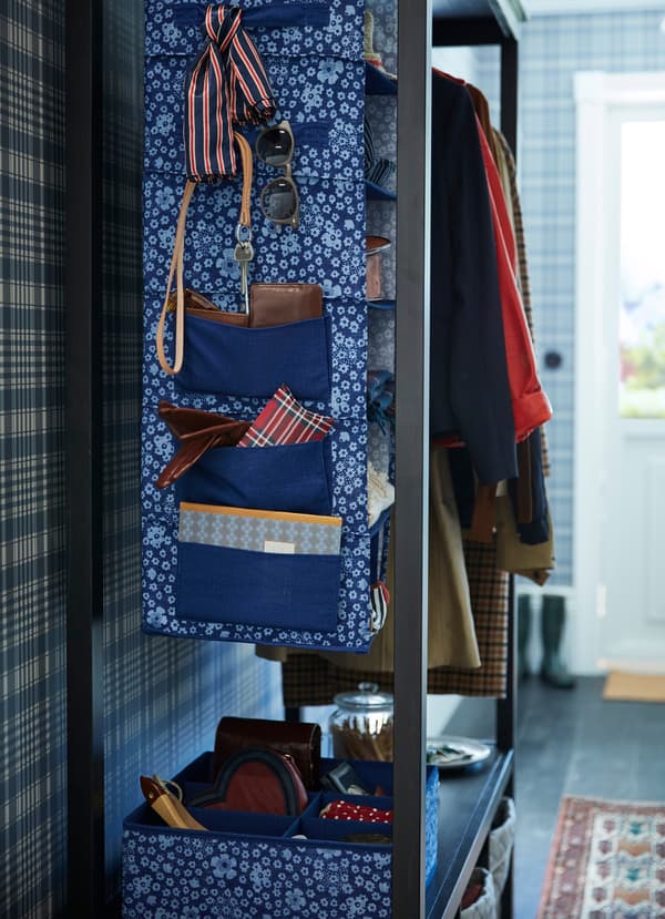 Corpul de depozitare suspendat și cutiile STORSTABBE, de la IKEA, sunt realizate din poliester și au modele florale, albastru, alb. Partea laterală are buzunare suplimentare pentru a putea ține mai multe obiecte.