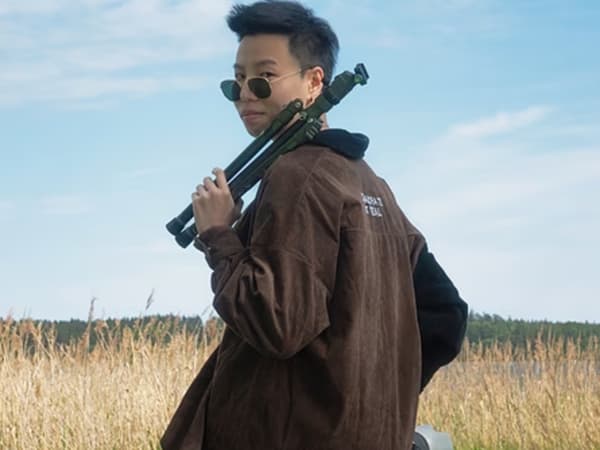 Coslayer Lee mit einem Kamerastativ in der Hand.