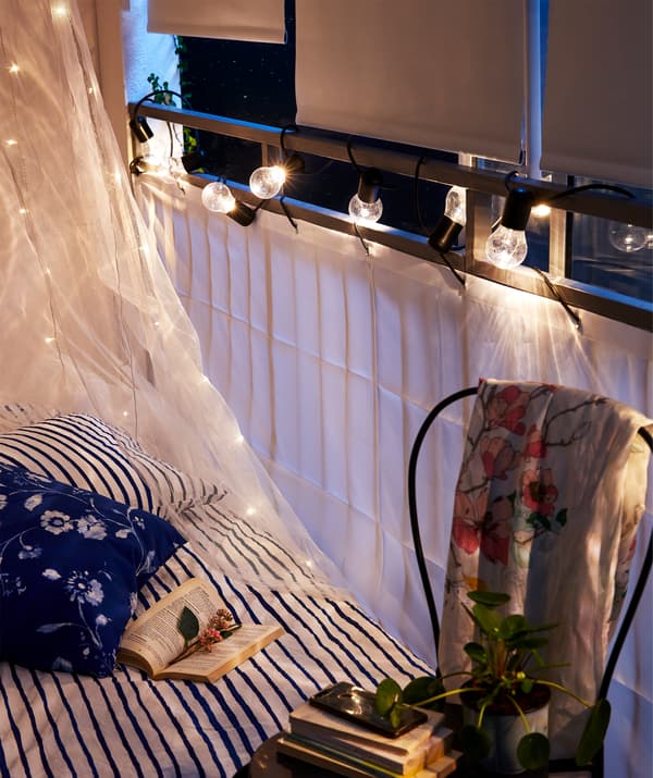Côté d'un lit jouxtant le bord du balcon avec brise-vue DYNING et store occultant.