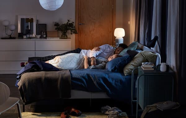 Couple cuddle asleep in a slattum upholstered bed