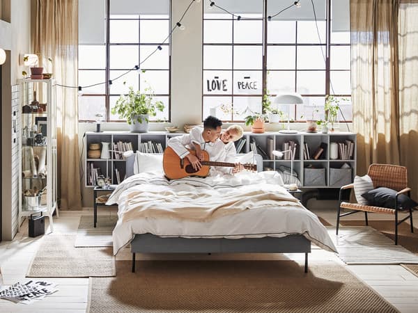 Couple happily plays an instrument in the bedroom.