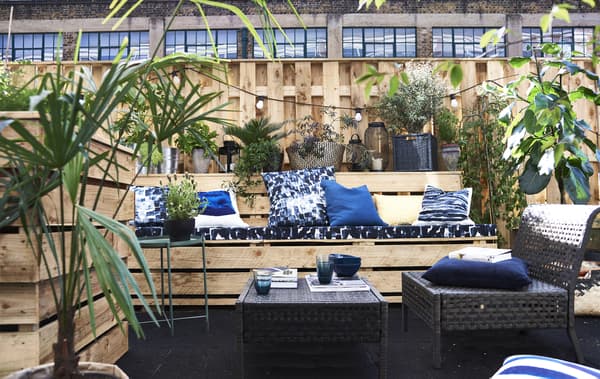 Coussins bleus et mobilier d’extérieur sur une terrasse.