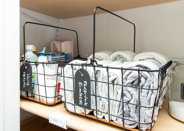 Couvertures à langer et trousse de toilette pour bébé dans des corbeilles en fil avec poignée PLEJA noires.