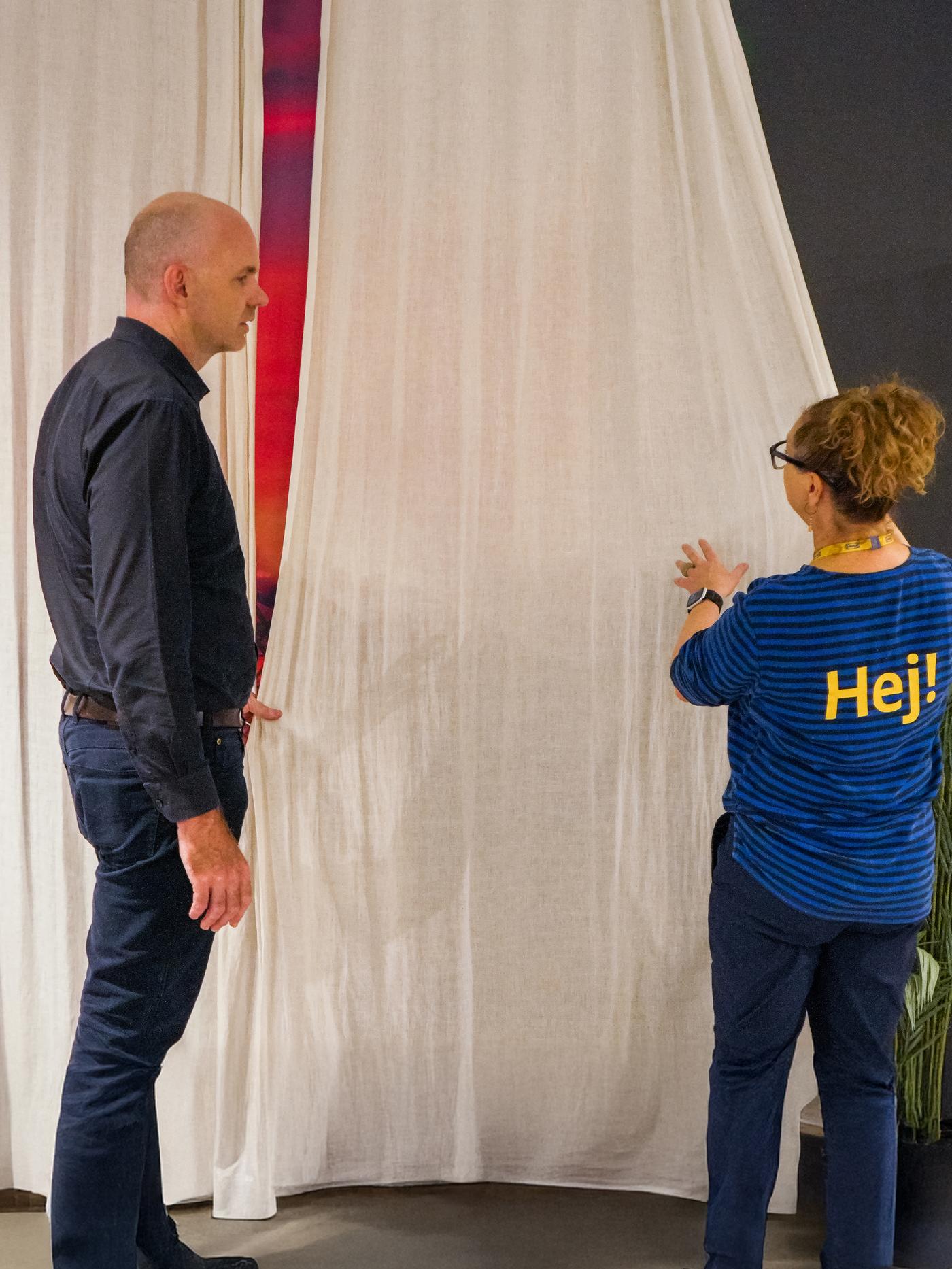 Coworker with business customer looking at curtains