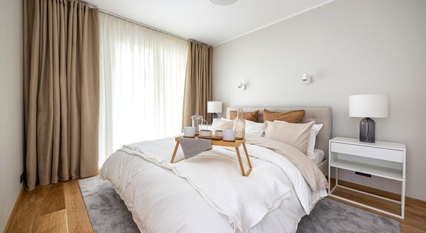 Cozy bedroom with beige curtains and breakfast tray on white bed