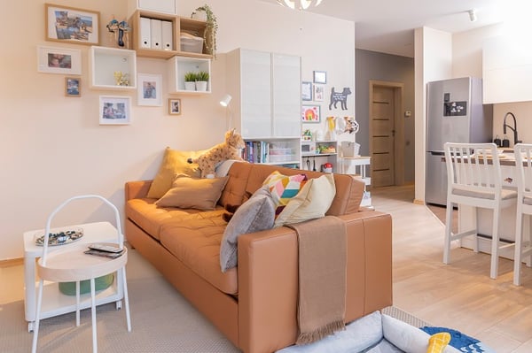 Cozy brown leather sofa with pillows in open-plan living room.