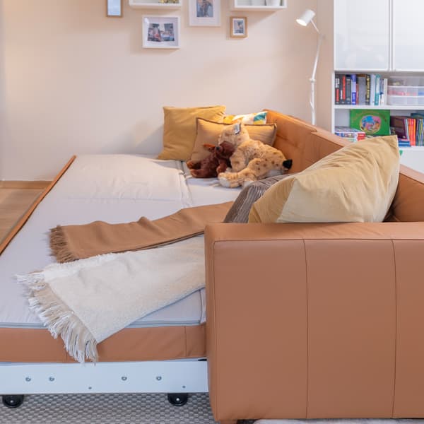 Cozy brown leather sofa with pillows in open-plan living room.
