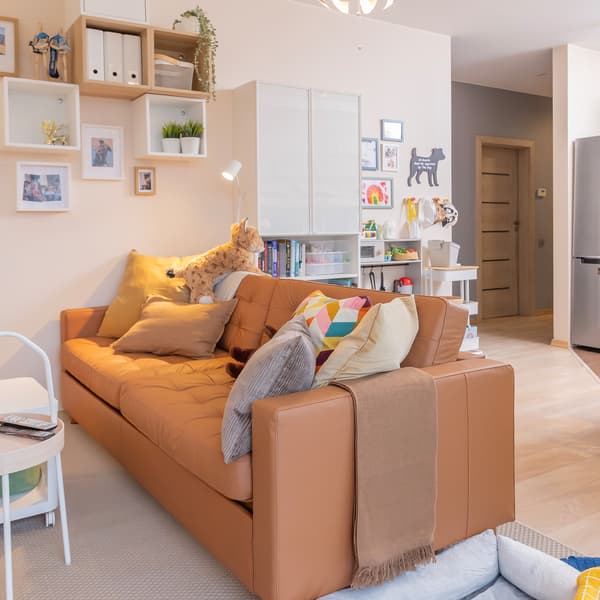 Cozy brown leather sofa with pillows in open-plan living room.