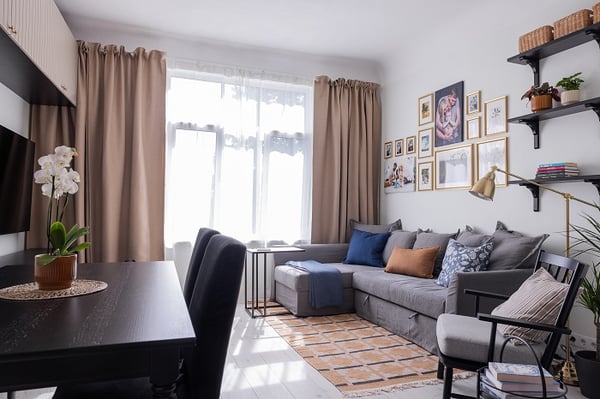 Cozy living room with gray sofa, gallery wall of family photos, shelves, and warm textiles