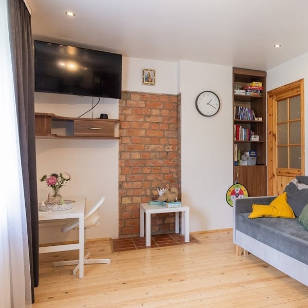 Cozy living space with work desk, TV, bookshelf, brick wall, and sofa