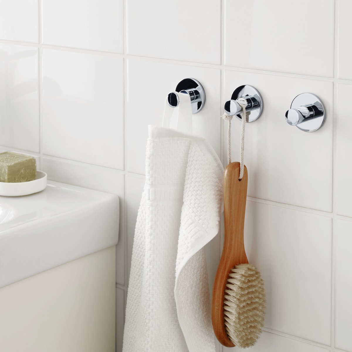 Crochets à ventouse avec une brosse et serviette de main blanche dans une salle de bain blanche
