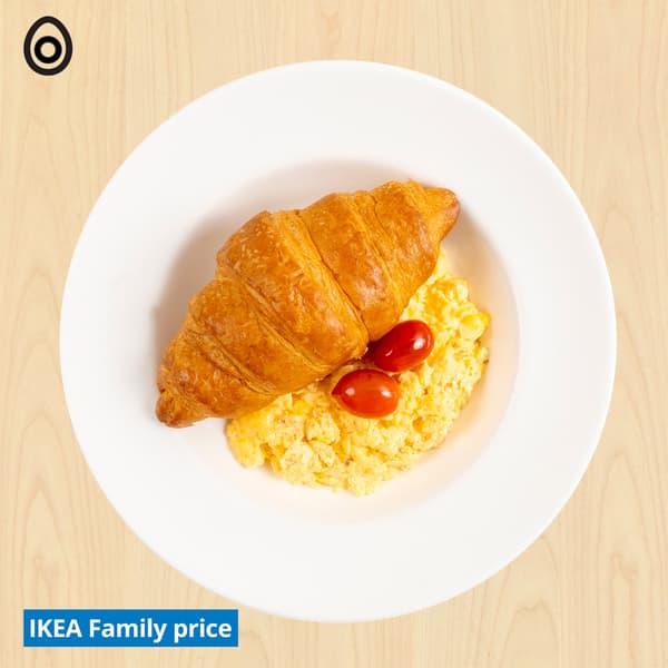 Croissant, scrambled egg and tomatoes with egg food symbols at top left corner. 