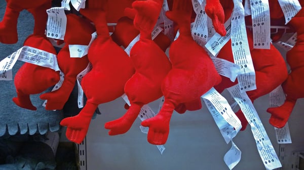 Crvene plišane igračke s etiketama vise na polici u robnoj kući.