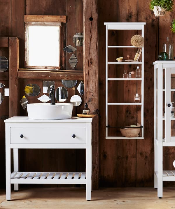 Cuarto de baño con paredes de madeira escura, toucador branco cun caixón e andeis brancos na parede.