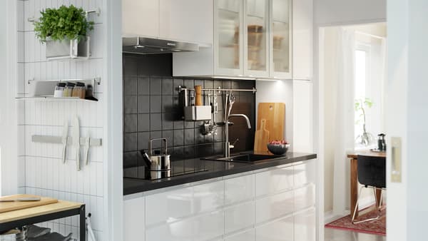 Cucina bianca con frontali cassetto bianco lucido, ante a vetro bianco lucido e piano di lavoro nero effetto pietra - IKEA