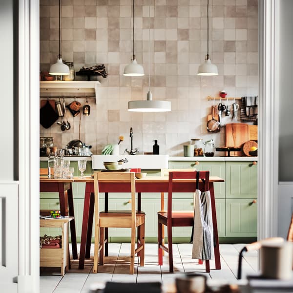 Cucina con frontali cassetto STENSUND verde chiaro e due tavoli PINNTORP con sedie PINNTORP.