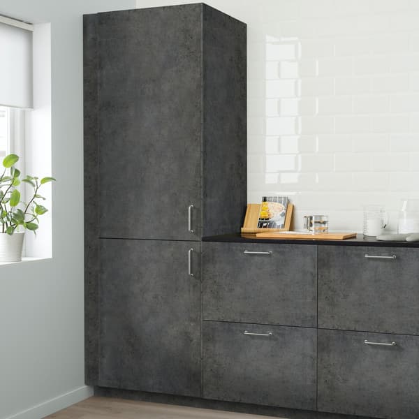 Cucina KALHYTTAN grigio scuro effetto cemento con una ciotola in vetro semicoperta con dentro un impasto, sopra a un piano di lavoro nero effetto minerale.