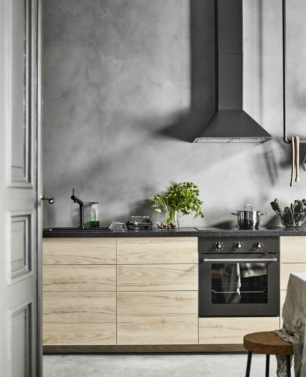 Cucina lineare con ante frassino con lo sfondo di una parete grigia effetto cemento - IKEA.