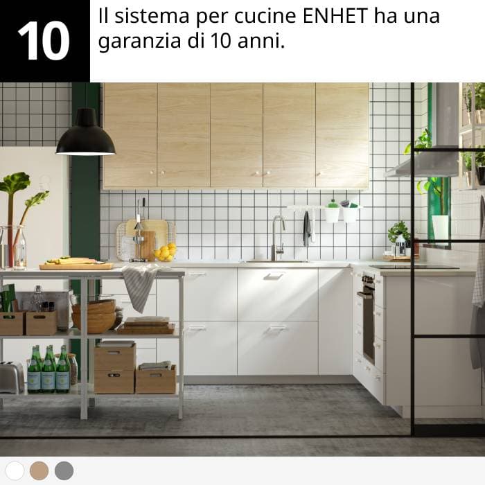 Cucina moderna con mobili bianchi, pensili in legno, isola in metallo, piante e utensili da cucina.