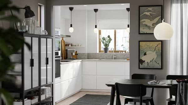 Cuisine aménagée blanche ouvert sur une salle à manger avec cadres au mur