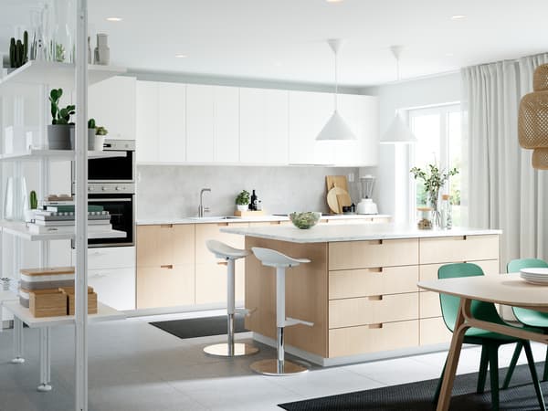 Cuisine avec des plans de travail EKBACKEN en stratifié blanc effet marbre, chaises vertes et divers appareils électroménagers.