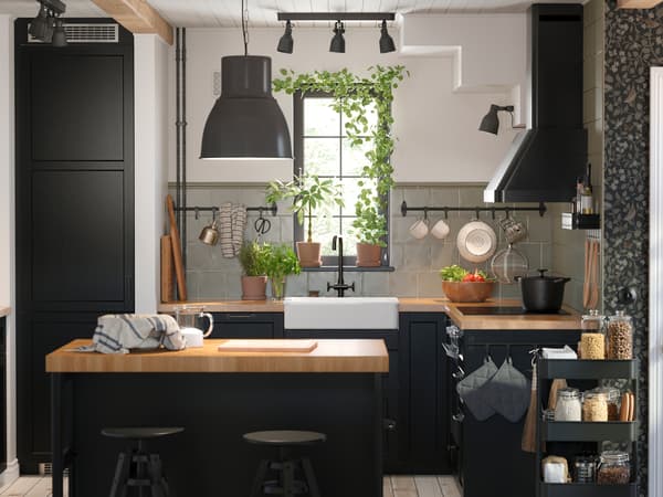 Cuisine avec façades LERHYTTAN en teinté noir, plans de travail KARLBY en chêne/plaqué et suspension HEKTAR en gris foncé.