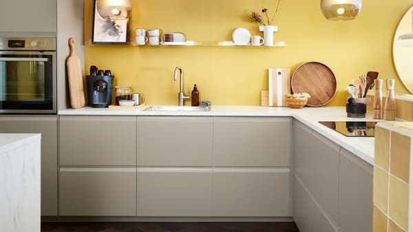 Cuisine avec faces de tiroirs UPPLÖV en beige foncé mat et plans de travail EKBACKEN en stratifié effet marbre blanc.