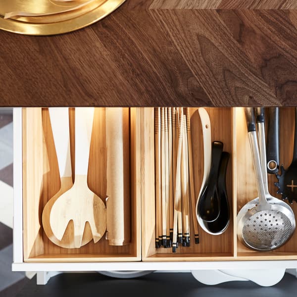 Cuisine caractérisée par un comptoir en noyer. Un tiroir est ouvert, et à l’intérieur se trouve un range-ustensiles qui favorise l’ordre et l’organisation.