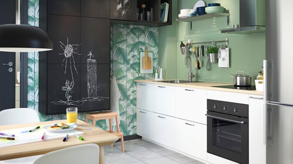 Cuisine moderne avec armoires blanches, accents verts et table à manger avec matériel créatif, près de l’évier et du four.