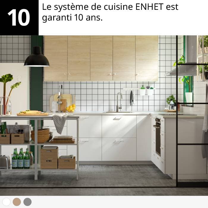 Cuisine moderne avec armoires blanches, meubles hauts en bois, îlot en métal, plantes et ustensiles.