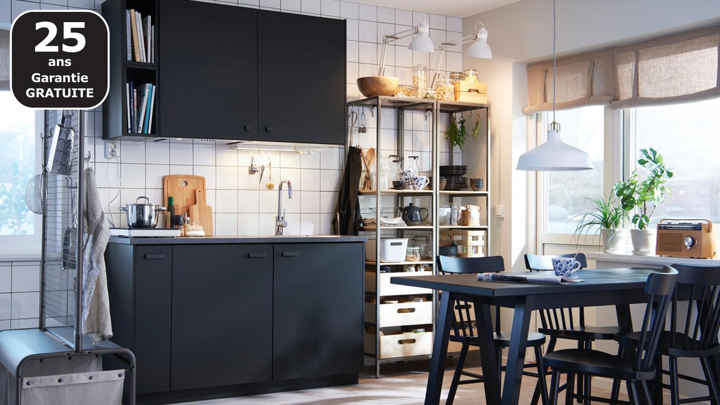 Cuisine monochrome avec éléments et table noirs et rangements métalliques ouverts.