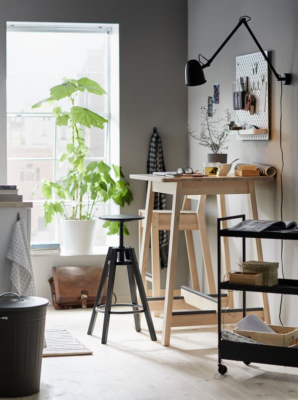Cuisine où une table de bar NORRÅKER sert d’espace de travail avec un tabouret de bar DALFRED et une desserte avec des accessoires liés.