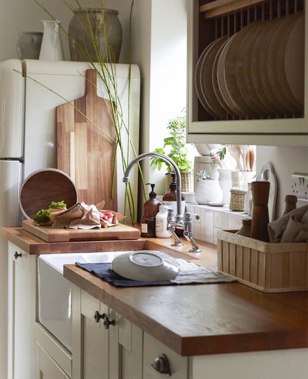 Cuisine rustique avec plans de travail en bois, éléments couleur crème et rangements ouverts.