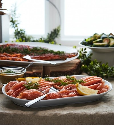 Cured salmon with slices of lemon and topped with dill in white plate.