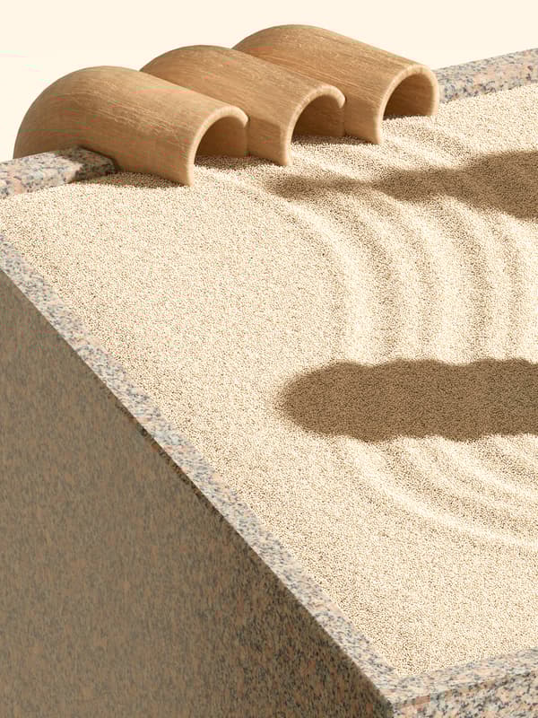 Curling trails lead from three wooden tubes on the edge of a granite box filled with yellow sand.