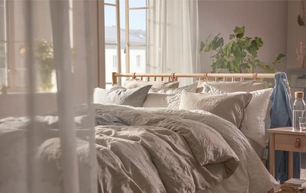 Curtain-softened light and fluffy duvets are ideal complements to the BJÖRKSNÄS birchwood bed and bedside table.