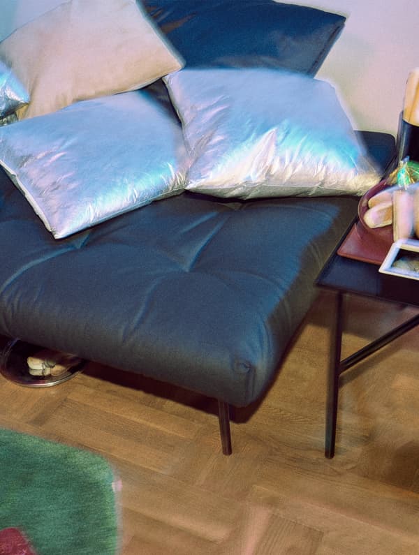 Cuscini con fodere color argento e beige resistenti all’acqua, sopra a un poggiapiedi nero FREKVENS - IKEA