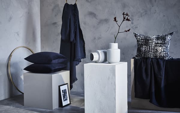 Cuscini e plaid blu in una stanza nelle tonalità del grigio e del bianco - IKEA
