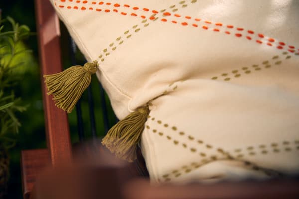 Cuscino beige chiaro con strisce e nappe